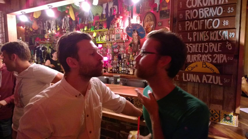 three men at a bar sharing a conversation