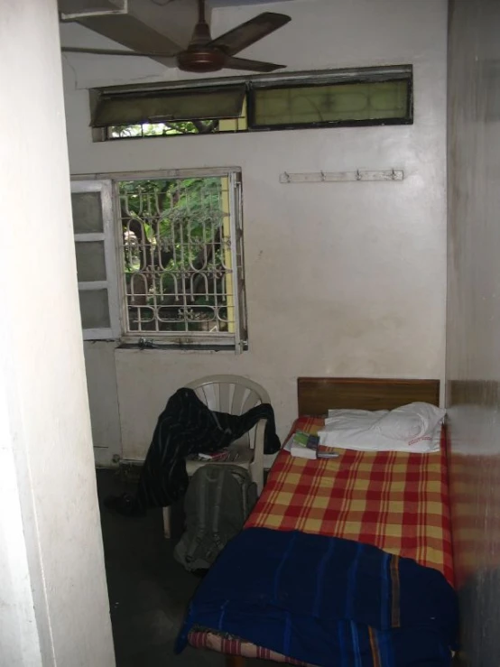 a bedroom with a checkered bedspread, and two windows