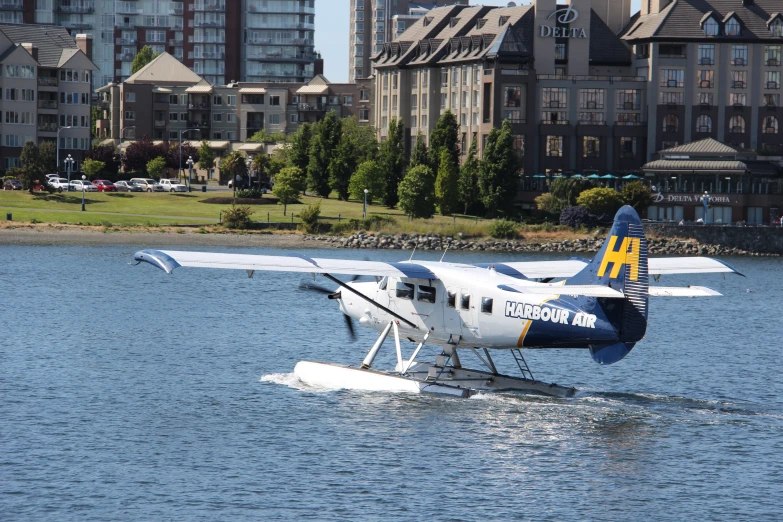 the small airplane is gliding down the river near buildings