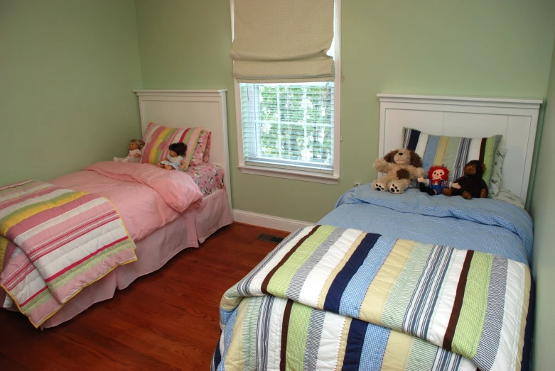 two beds in a room that has light green walls and hardwood floors