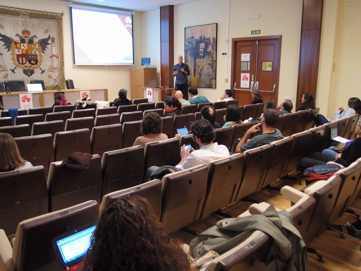 people sitting in chairs with laptops and electronic devices