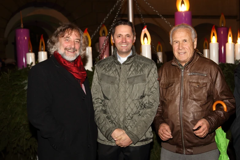 three people standing together next to candles