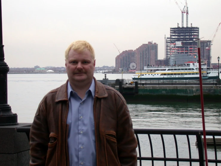 a man standing by the water wearing a jacket