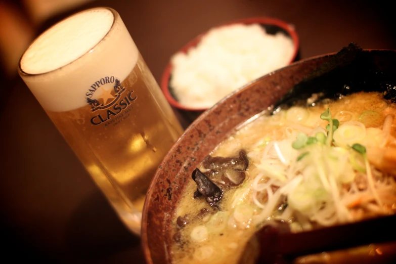 a bowl of food, beer and a cup sitting on a table