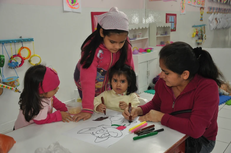 four girls making pictures with crayons and paper