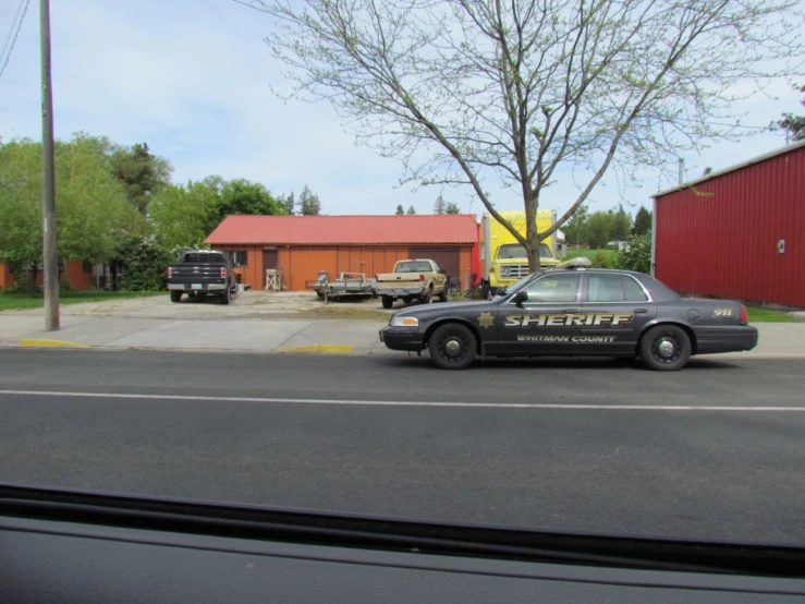 a black sheriff car is parked outside a red building