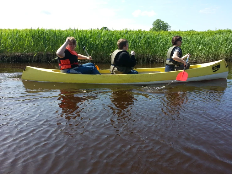 three people in a yellow canoe on the water