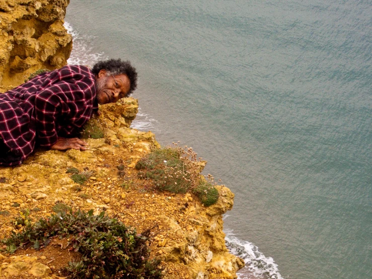 a man laying down on the edge of a cliff