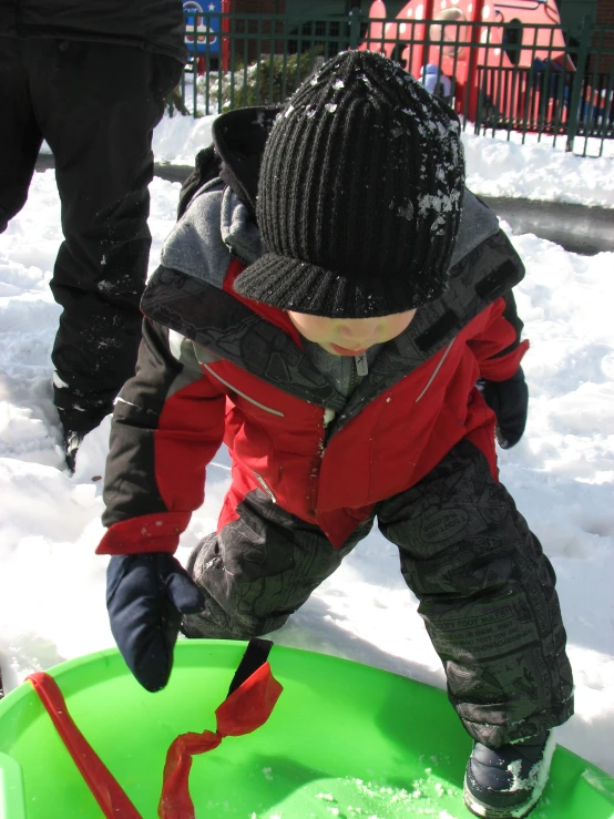 a little boy standing on top of a snow covered ground