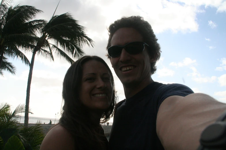 a man and woman taking a selfie under palm trees