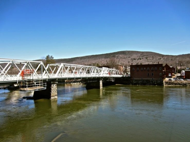 a white bridge over a river leading to buildings