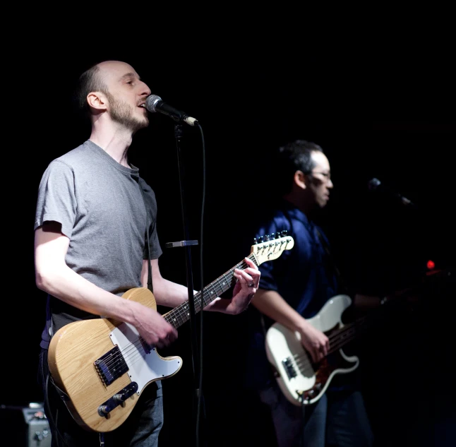 two men are playing guitars on stage