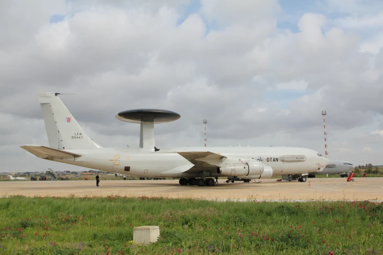 a white airplane sits on the runway in front of some people