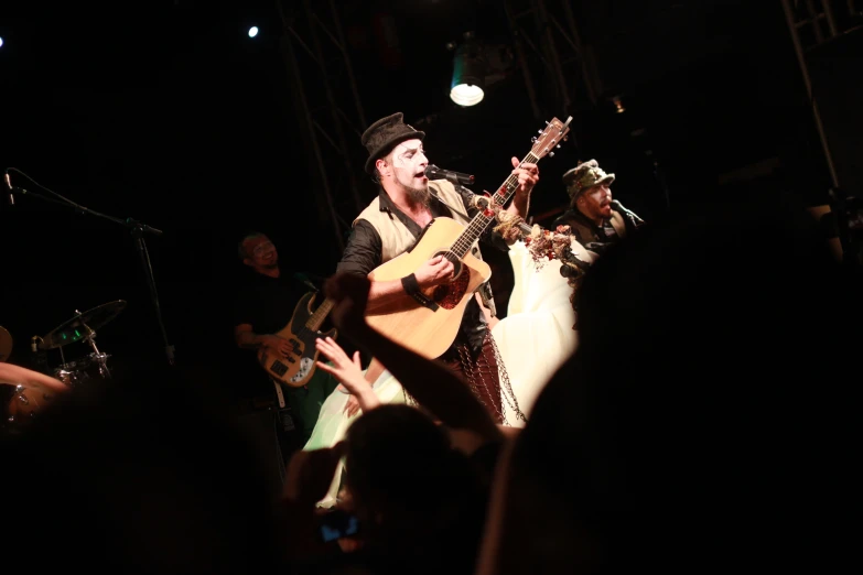 a man on stage with a guitar and a group of people around