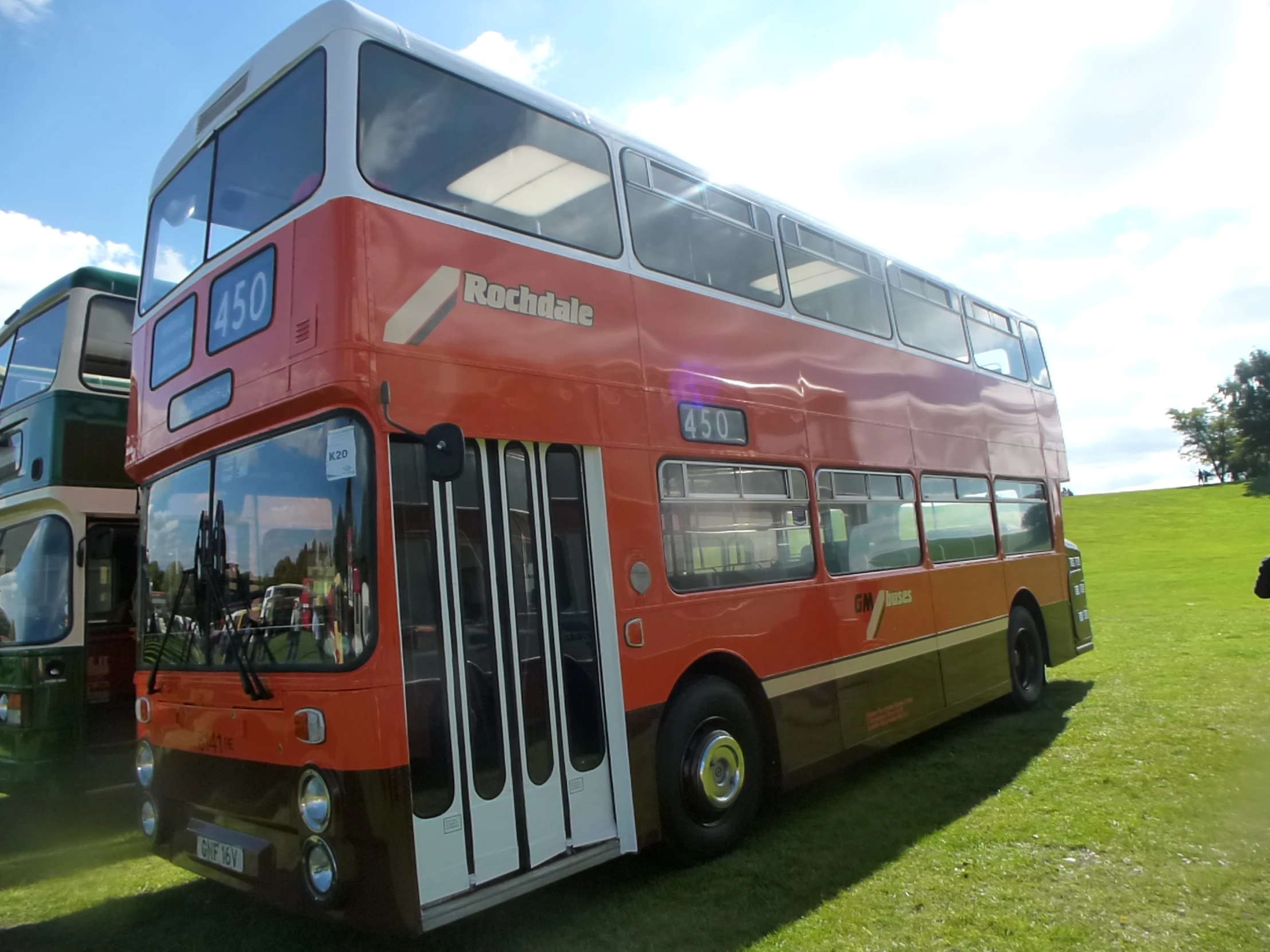 two double - decker buses are parked in the middle of a grassy field