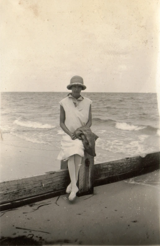 a black and white po of a person with a hat on sitting by the water