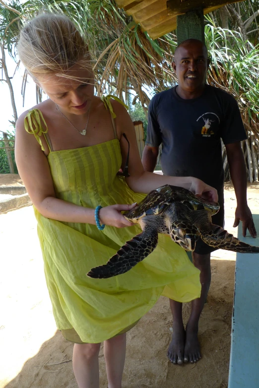 two people in green dress holding a green turtle