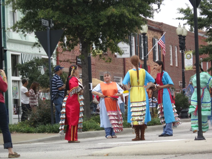 three women are walking down the street, with various outfits and decorations on