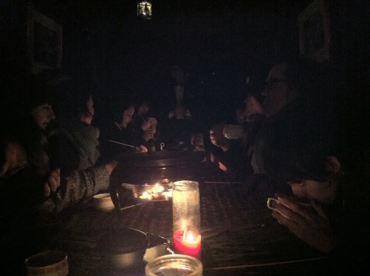 people are sitting at a table with candles