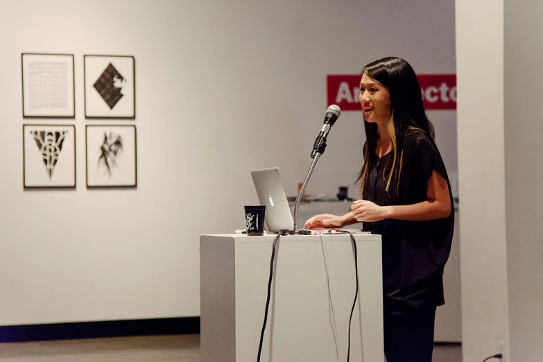 a woman is standing at a podium with her laptop