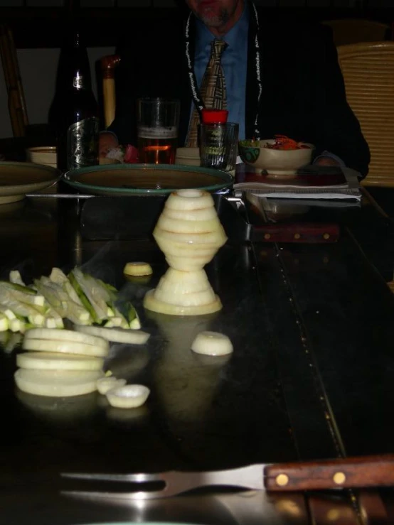 man at table in dark place, chopping onions on counter