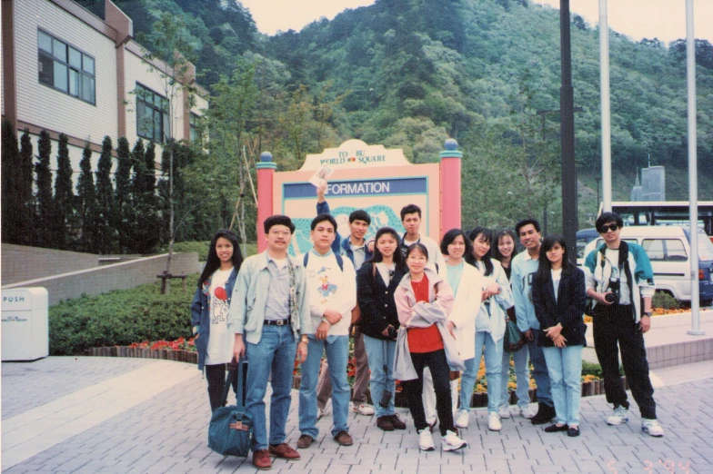 a group of people standing in front of a sign with a large mountain behind them