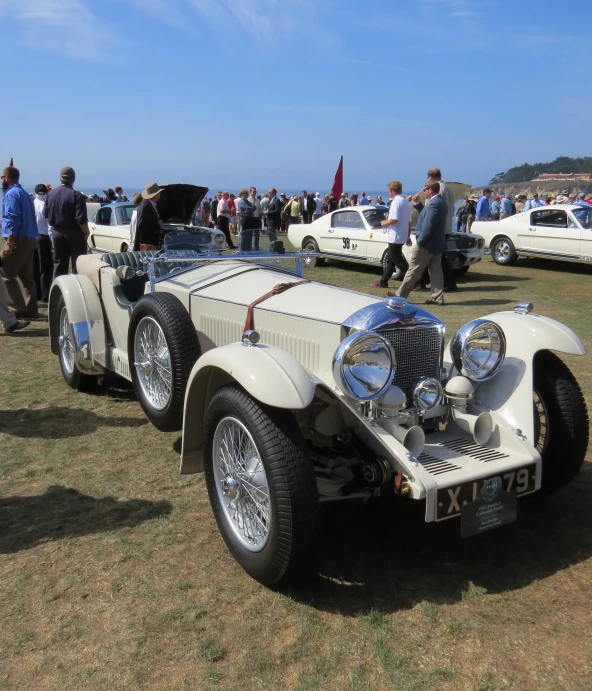 an antique white car is parked at the event