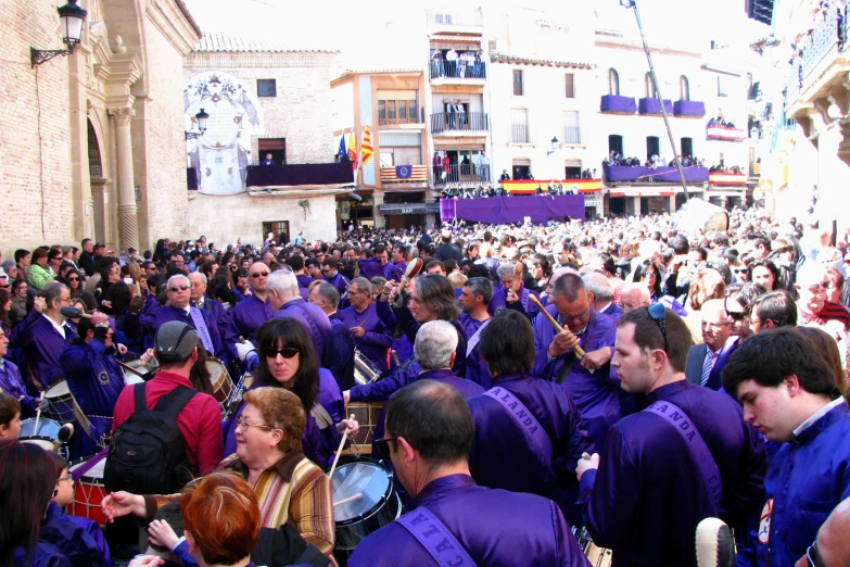 large group of people standing in the street with one person holding a guitar