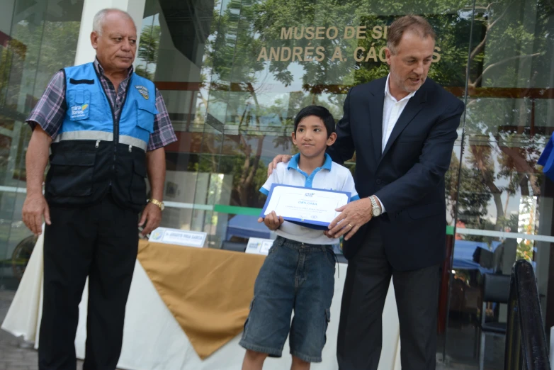 a man giving an award to a boy