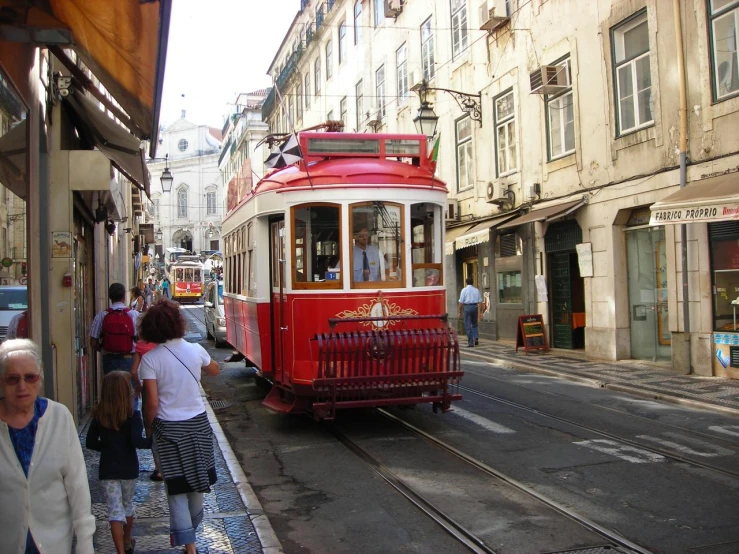 the red trolley is riding down the busy street