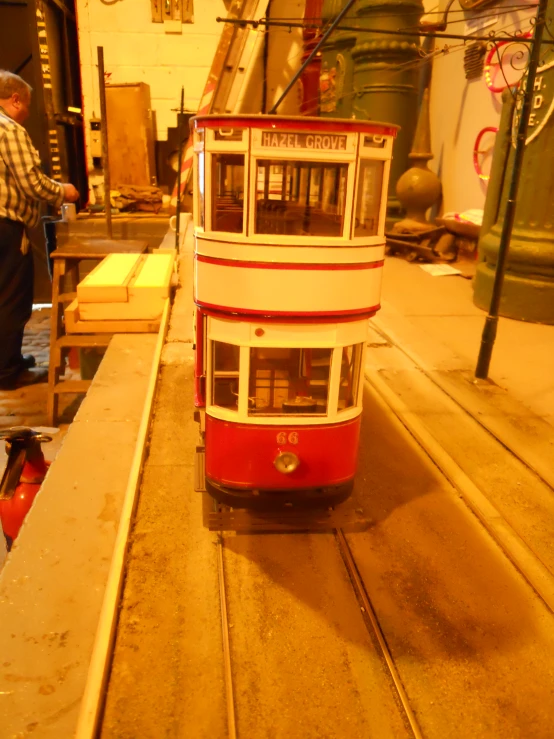 a red and white two level tram that is on a rail road