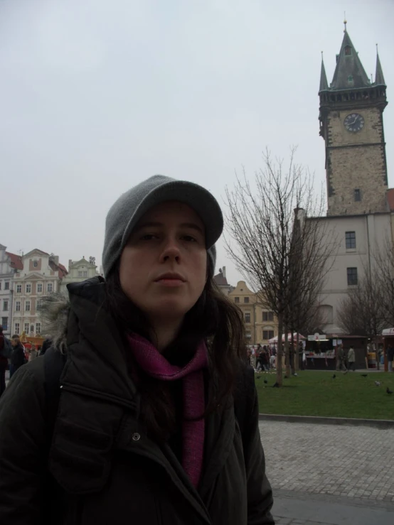 woman with purple shirt and hat in front of a tower