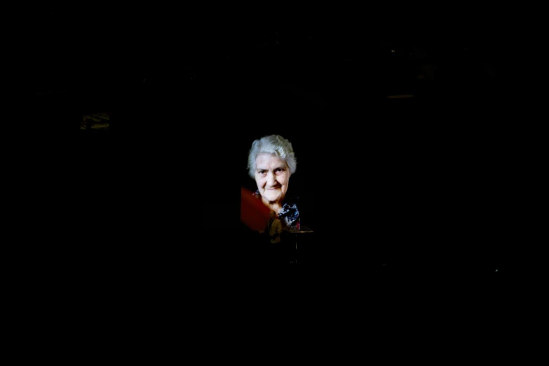 an old woman sits in the dark alone