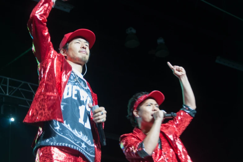 two men in sequin outfits and red hats