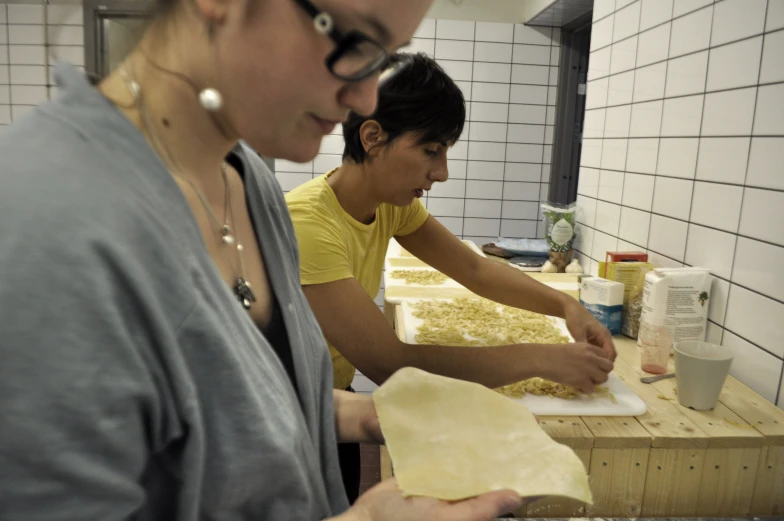 two women making dough in a commercial kitchen