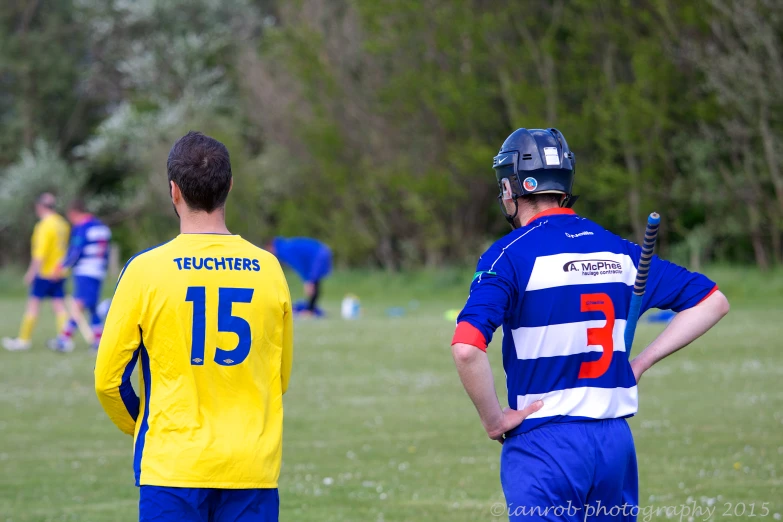two soccer players talk while one player stands
