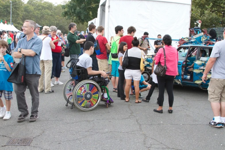 a group of people standing around next to a blue car