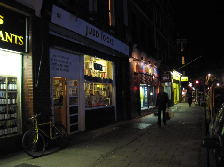 a couple of people walking down a street past a store