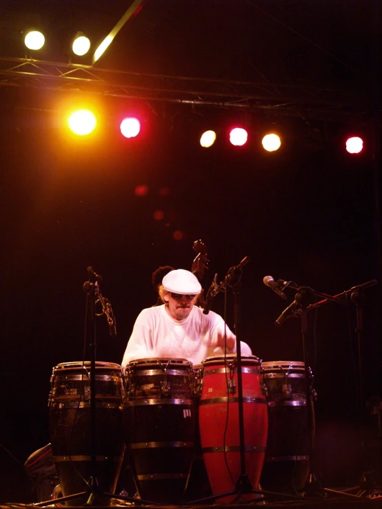 a man sitting at a drum set in front of three microphones