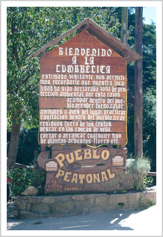 a wooden sign for pueblo petanol in front of trees