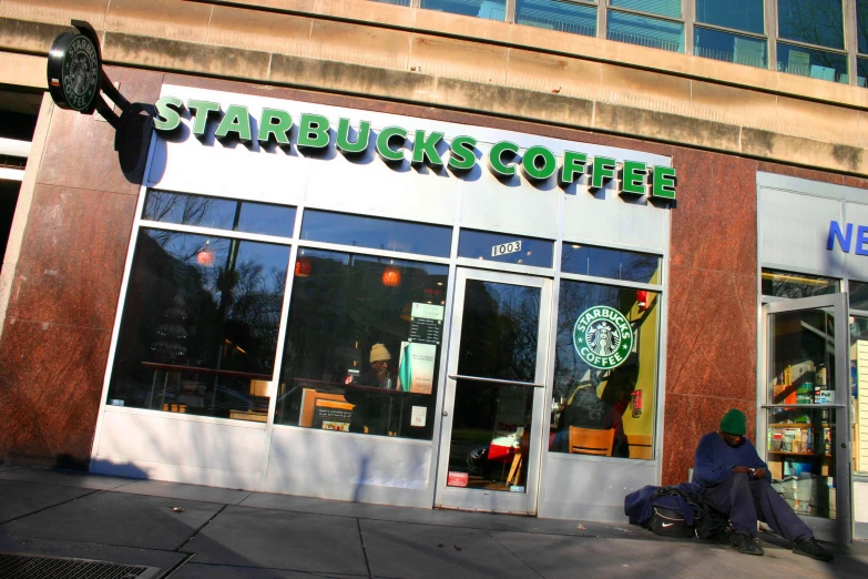 a person sitting outside of a starbucks on a sidewalk