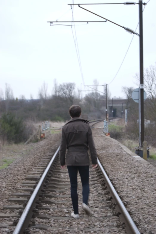 a person standing on a train track with power lines above