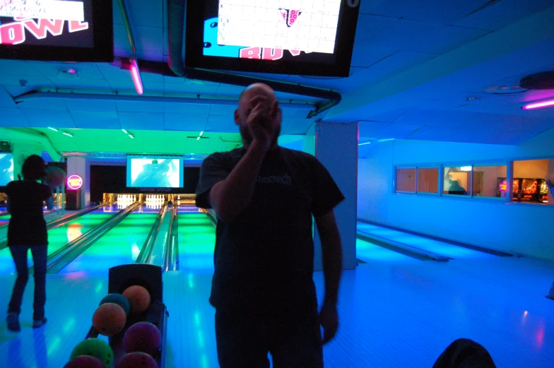 two men bowling on a brightly lit bowling alley