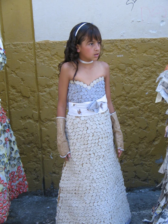 a little girl wearing a dress and gloves on the street