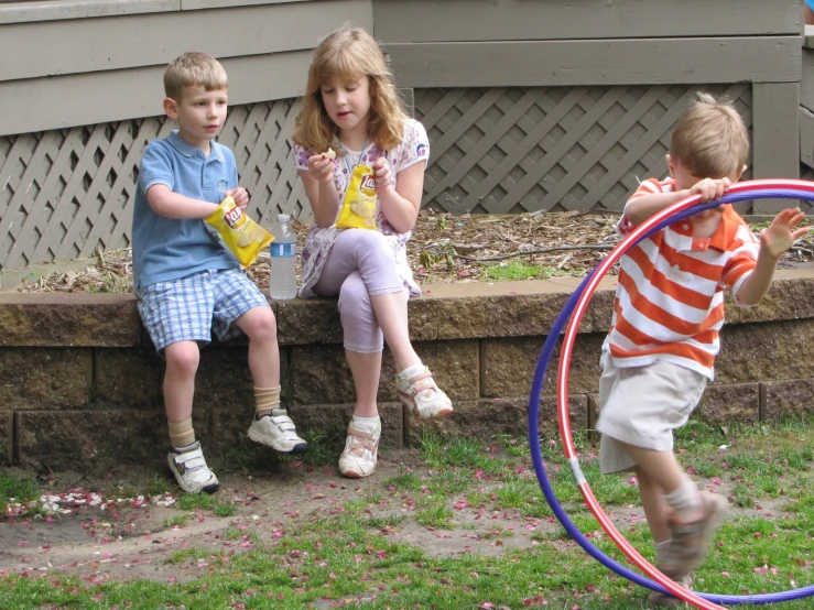 three small children playing with their toys outside