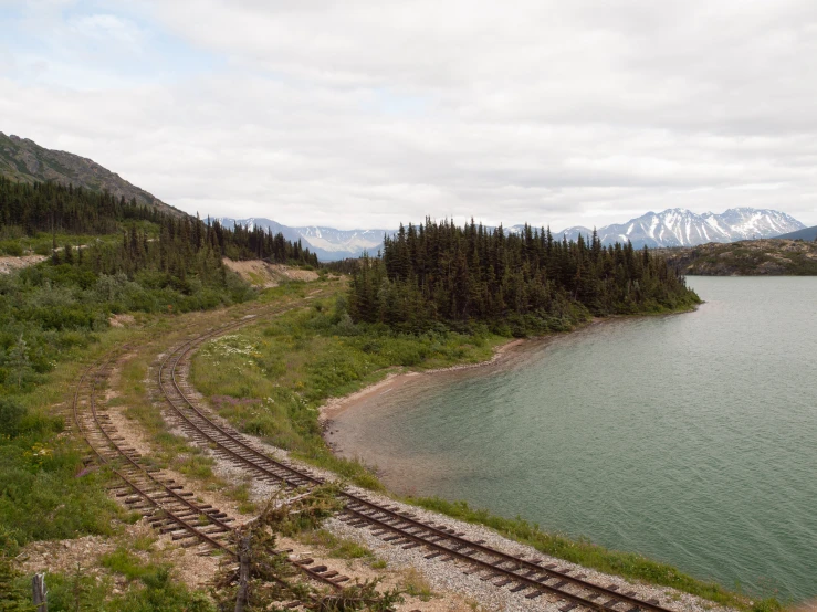 a long and winding railroad trail near a mountain lake