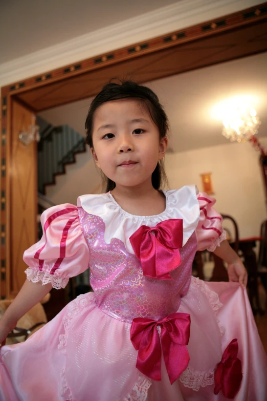 a little girl is wearing a pink dress