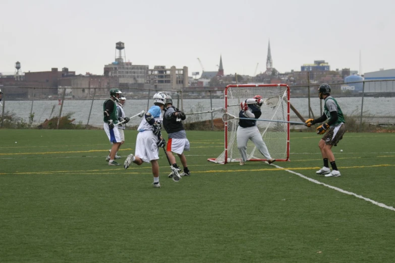 s wearing lacrosse helmets standing in front of a goalie net