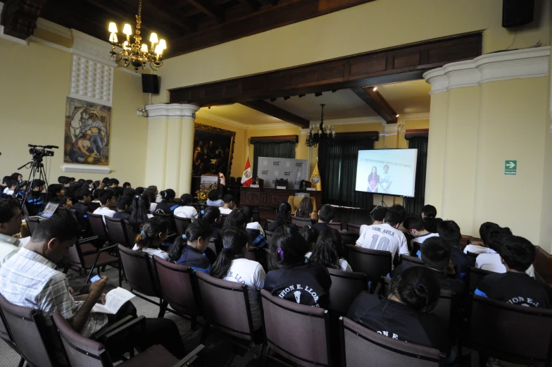 several people in chairs listening to a speaker