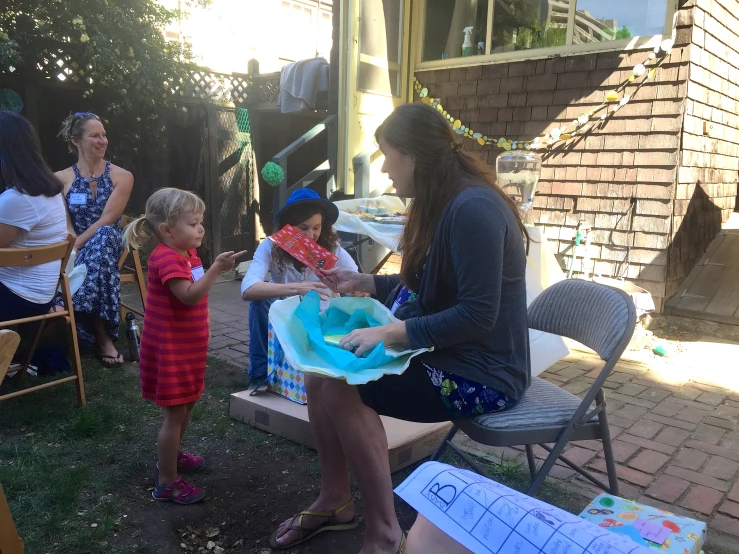 a woman handing soing to a little girl on her lap